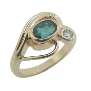 14K Yellow gold ring bezel set with a 0.817 carat oval green tourmaline and accented with one bezel set 0.08 carat natural very good cut round brilliant cut diamond, G-H, SI1.