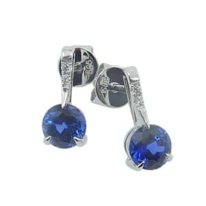 14K White gold drop earrings claw set with 5mm round Chatham blue sapphires, 1.35 total carat weight, and lab grown diamonds, 0.03 total carat weight.