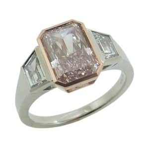 14K White and rose gold custom engagement ring bezel set with a 2.07 carat radiant cut fancy intense pink lab grown diamond, VS1, and accented with two trapezoid lab grown diamonds, 0.63cttw, E/F, VS+.