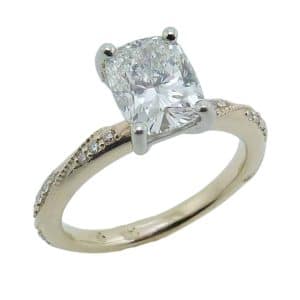 14K Yellow and white gold solitaire engagement ring with milgrain vine on the band claw set in the centre with a 1.62 carat, G, VS1 cushion brilliant cut lab grown diamond and accented with twenty-two round brilliant cut lab grown diamonds, 0.133cttw, E/F, VS+.