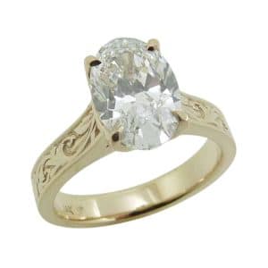 14K Yellow gold engraved solitaire engagement ring claw set with a 2.02 carat, D, VVS2 oval brilliant cut lab grown diamond.