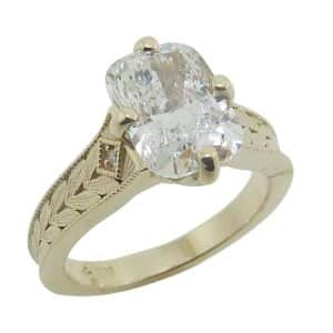 14K Yellow gold custom engraved solitaire engagement ring claw set with a 2.51 carat, D, VVS2 elongated cushion brilliant cut lab grown diamond accented on the band with two bead set round brilliant cut lab grown diamonds, 0.008cttw D/E, VS+.
