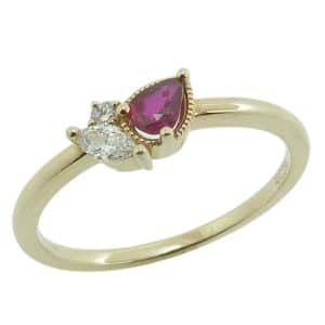 14K Yellow gold asymmetrical lady's ring with milgrain detail claw set with a pear shape ruby, 0.18 carat; one round brilliant cut diamond, 0.02 carat; and one marquise natural diamond, 0.08 carat.