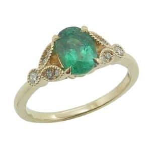 14K Yellow gold lady's ring claw set with a 0.72 carat oval emerald and accented on each side with eight natural round brilliant cut diamonds, 0.105cttw, G/H, SI.