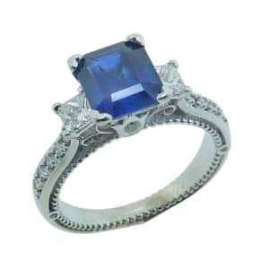 Estate item - 14K White gold lady's ring claw set in the centre with a 1.51 carat emerald cut unheated blue sapphire accented with two princess cut diamonds, 0.20cttw, and ten round brilliant cut diamonds, 0.15cttw.