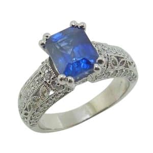 Estate item - Platinum lady's ring claw set with a 2.25 carat emerald cut blue sapphire and accented with sixty-six round brilliant cut diamonds, 0.15 total carat weight.