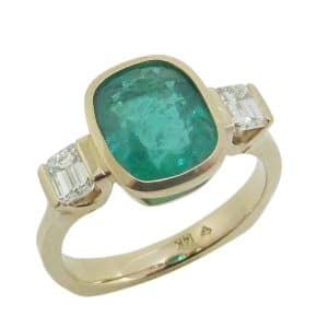 14K Yellow gold custom lady's ring bezel set in the centre with a 2.46 carat emerald and accented with two channel set natural emerald cut diamonds, 0.477cttw, G/H, VS2-SI1.