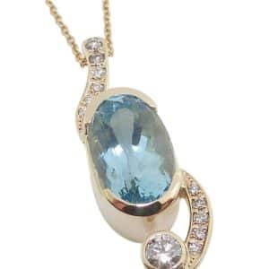 14K Yellow gold Studio Tzela custom pendant semi-bezel set with a 3.97 carat oval aquamarine and accented with eleven pave and bezel set natural round brilliant cut diamonds, 0.14cttw, G/H, SI-12.
