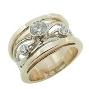 14K Yellow and white gold Studio Tzela lady's diamond band bezel set with a natural round brilliant cut diamond, 0.416 carat, I, SI1, and two round brilliant cut natural diamonds, 0.105cttw, G/H, SI1.